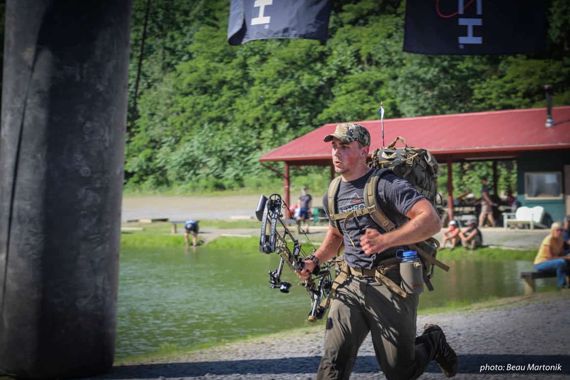 Man running with pack and bow in Hike to Hunt fitness competition.