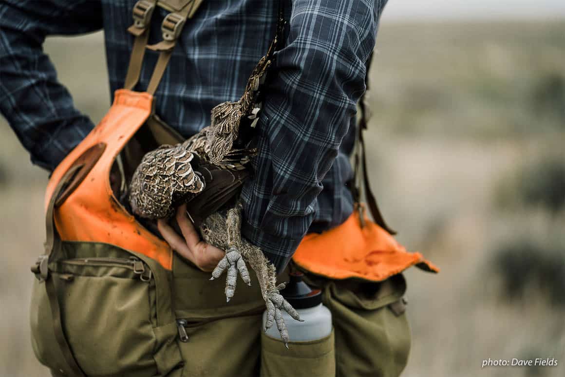 Garrett Mikrut places a bird into a game pouch, shot while upland bird hunting in eastern Montana.