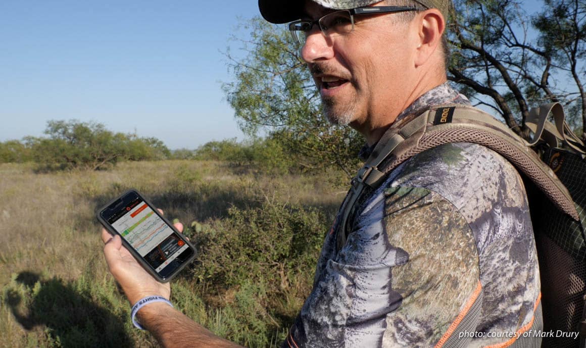 Image of Mark Drury of Drury Outdoors using the DeerCast app on his phone while hunting.