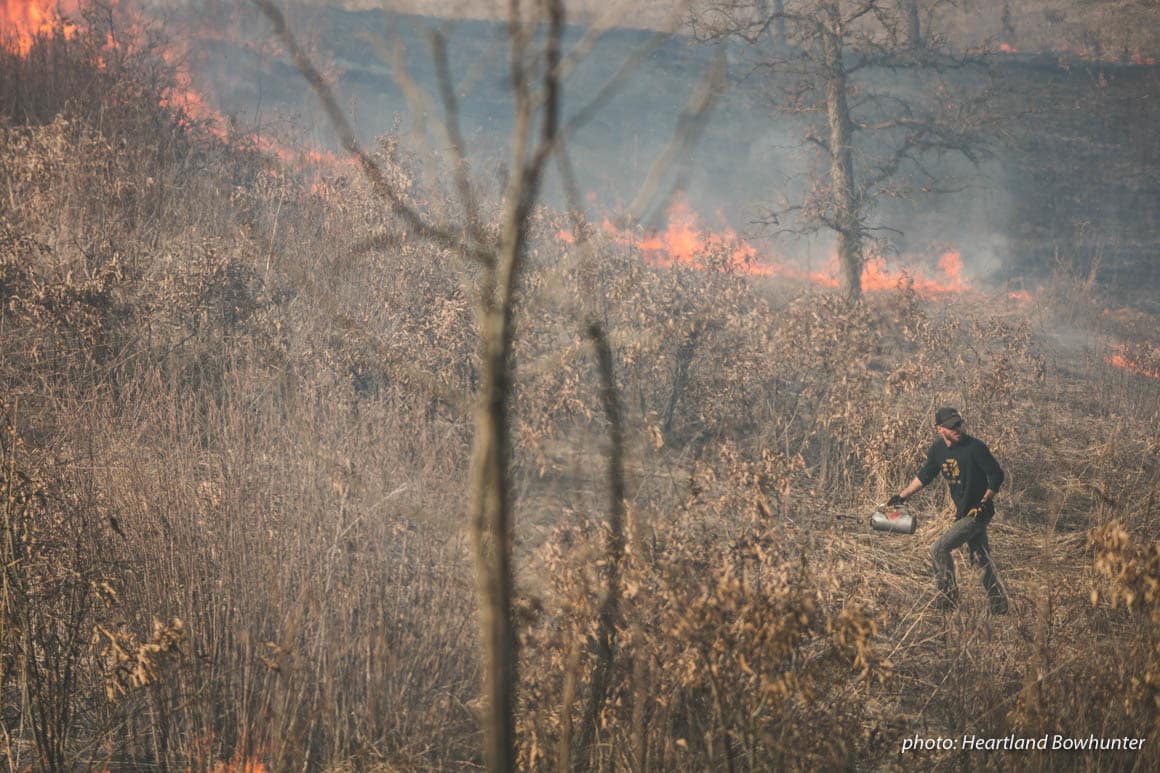 Man in field doing controlled burn to halp manage land for hunting.