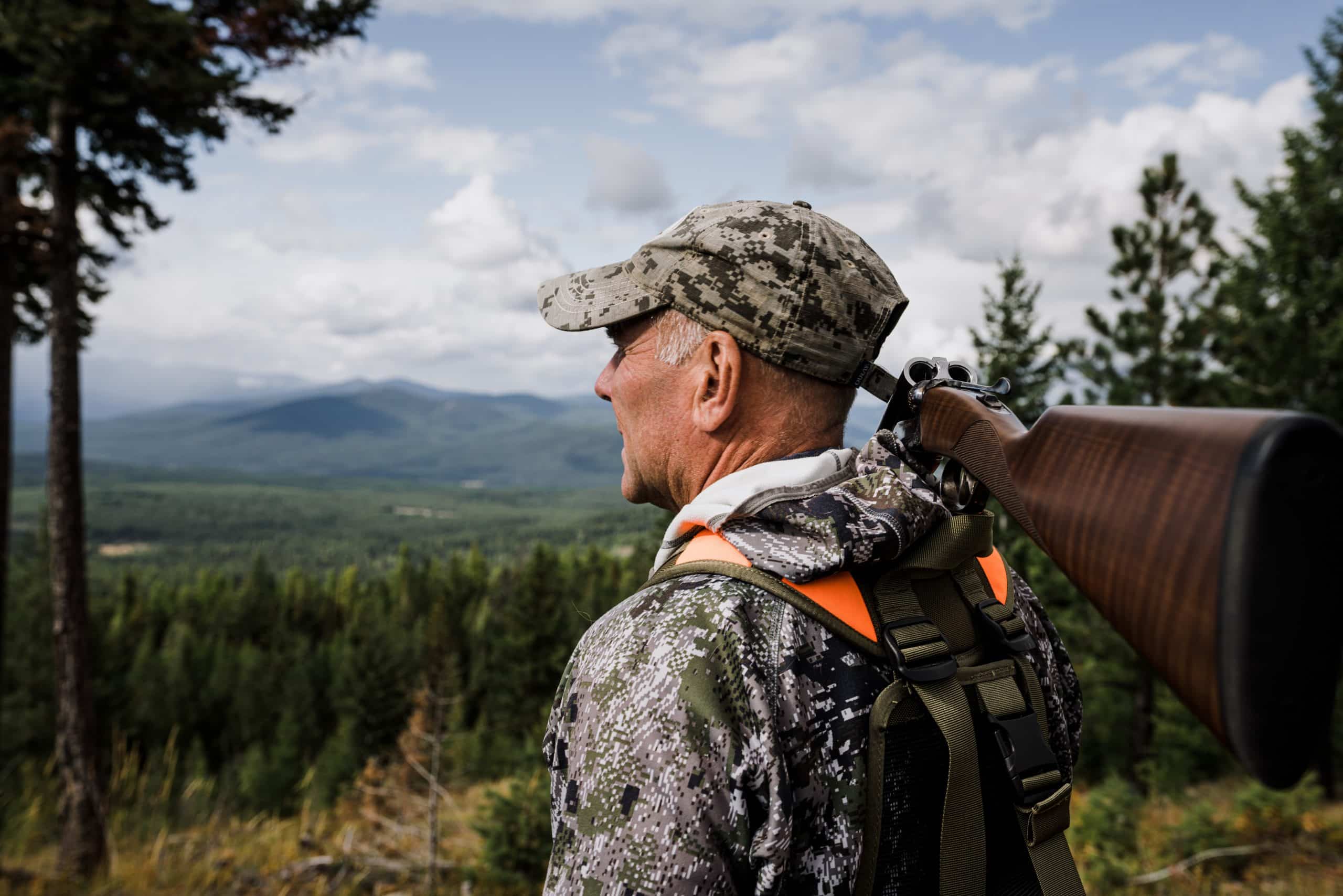 Montana outfitter Tim Linehan holds a shotgun and looks out over the valley.