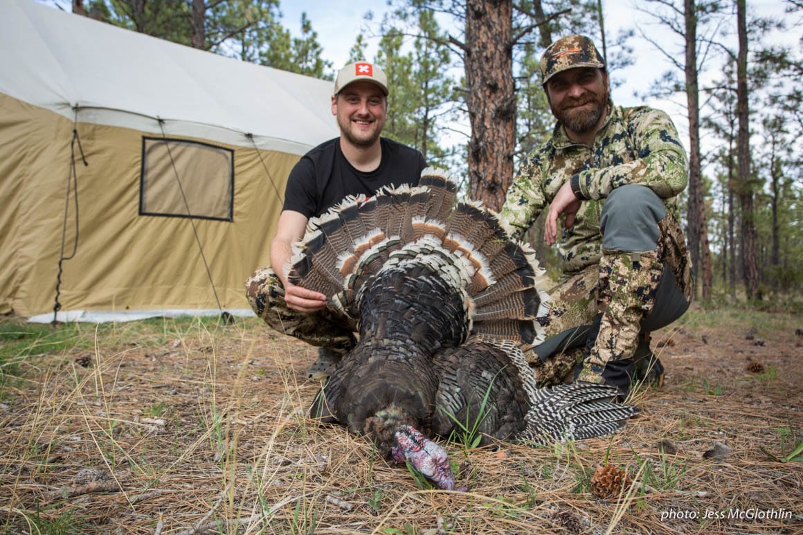 Two hunters pose with a turkey they shot while hunting in Montana.