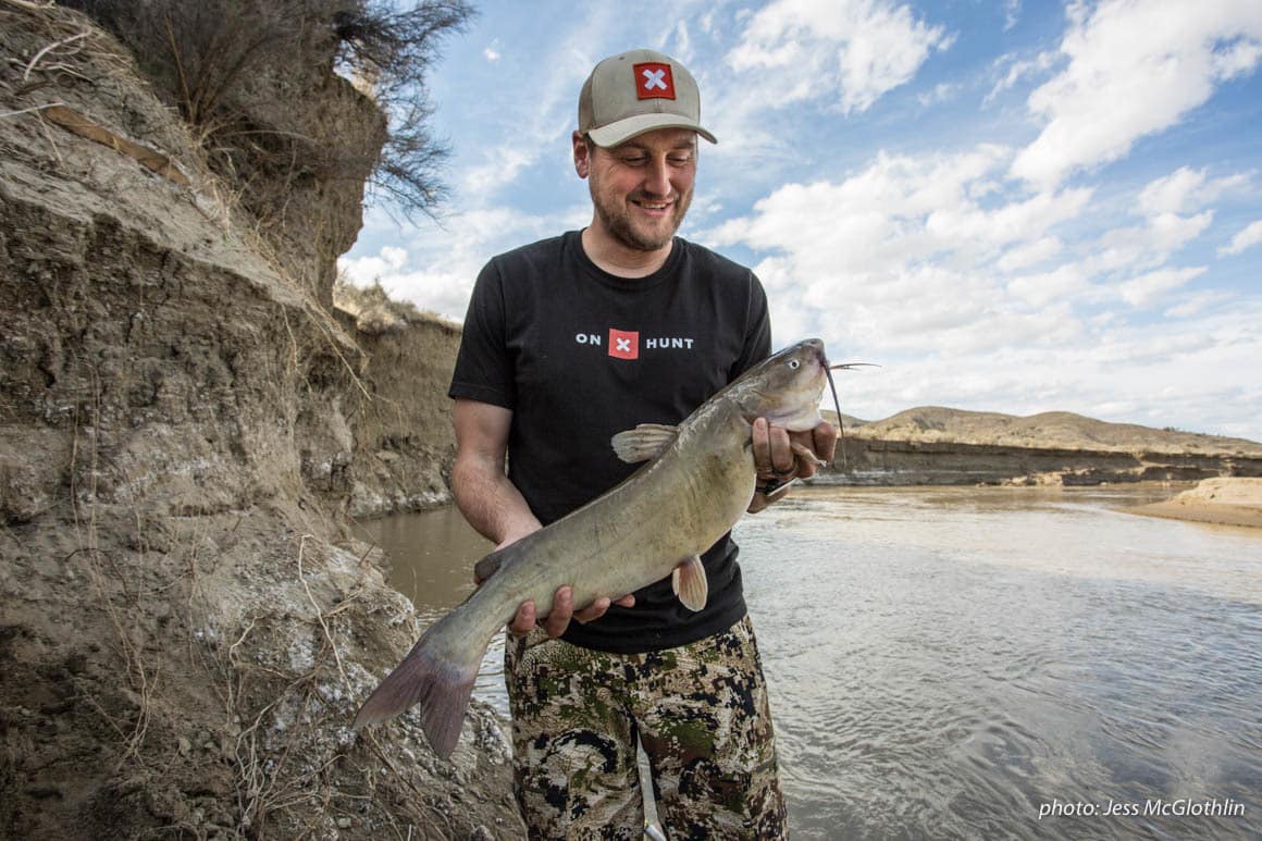 A man smiles at a catfish he caught while fishing on the Musselshell River in Montana.