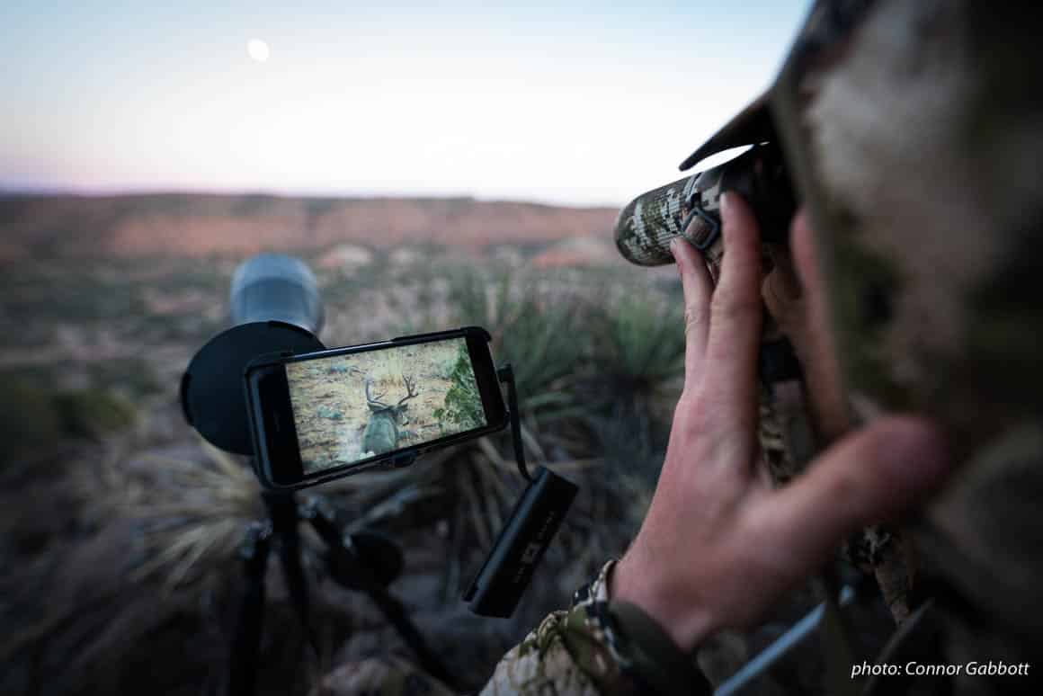 Man watches deer through phone scope while hunting in Arizona.