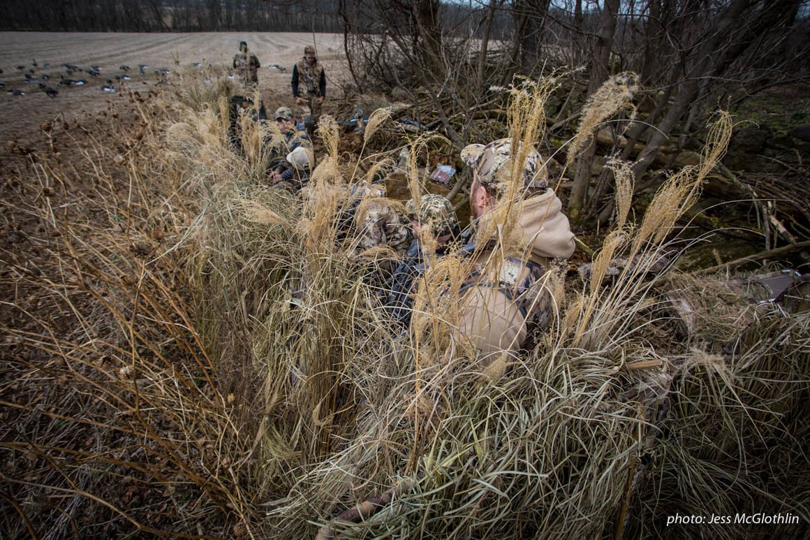 Waterfowl hunters in a goose blind in a field during winter.