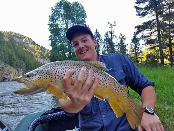 Man holding large brown trout caught while fly fishing on Montana's Smith River.