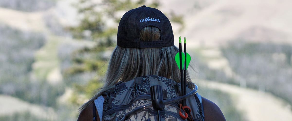 Female bowhunter with onX Hunt cap with camouflage backpack.