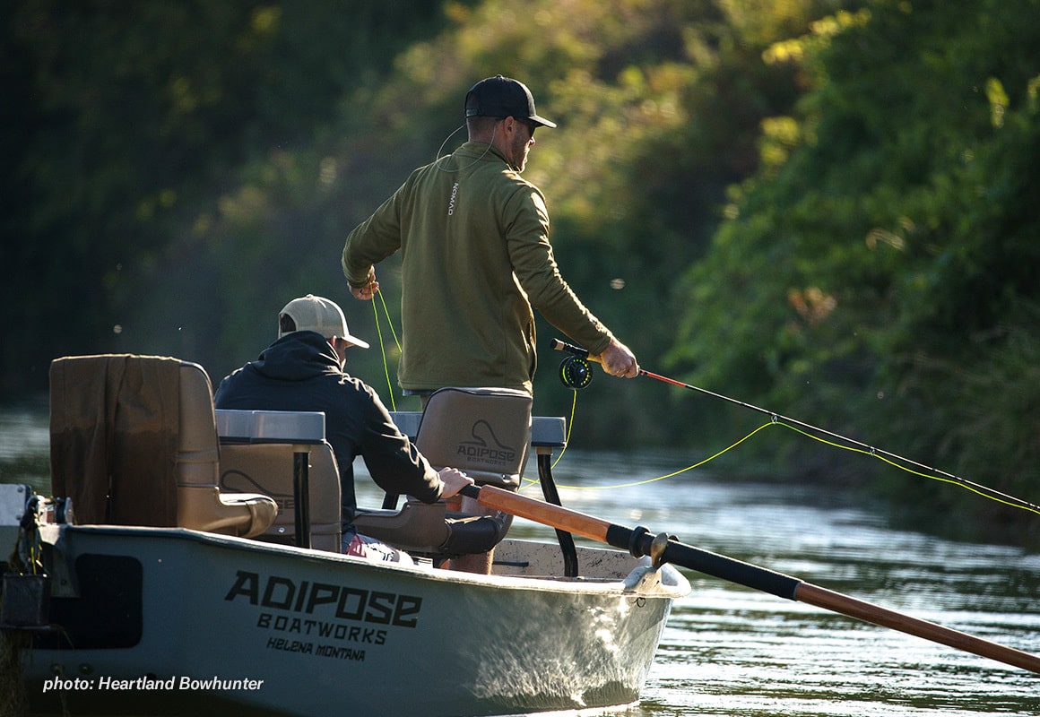 Two men fly fishing from a driftboat in the summertime.