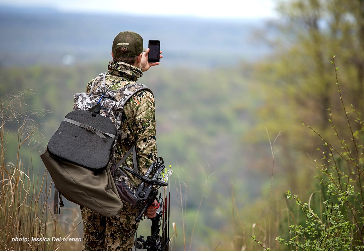 Bowhunter looking at the onX Hunt App in the backcountry