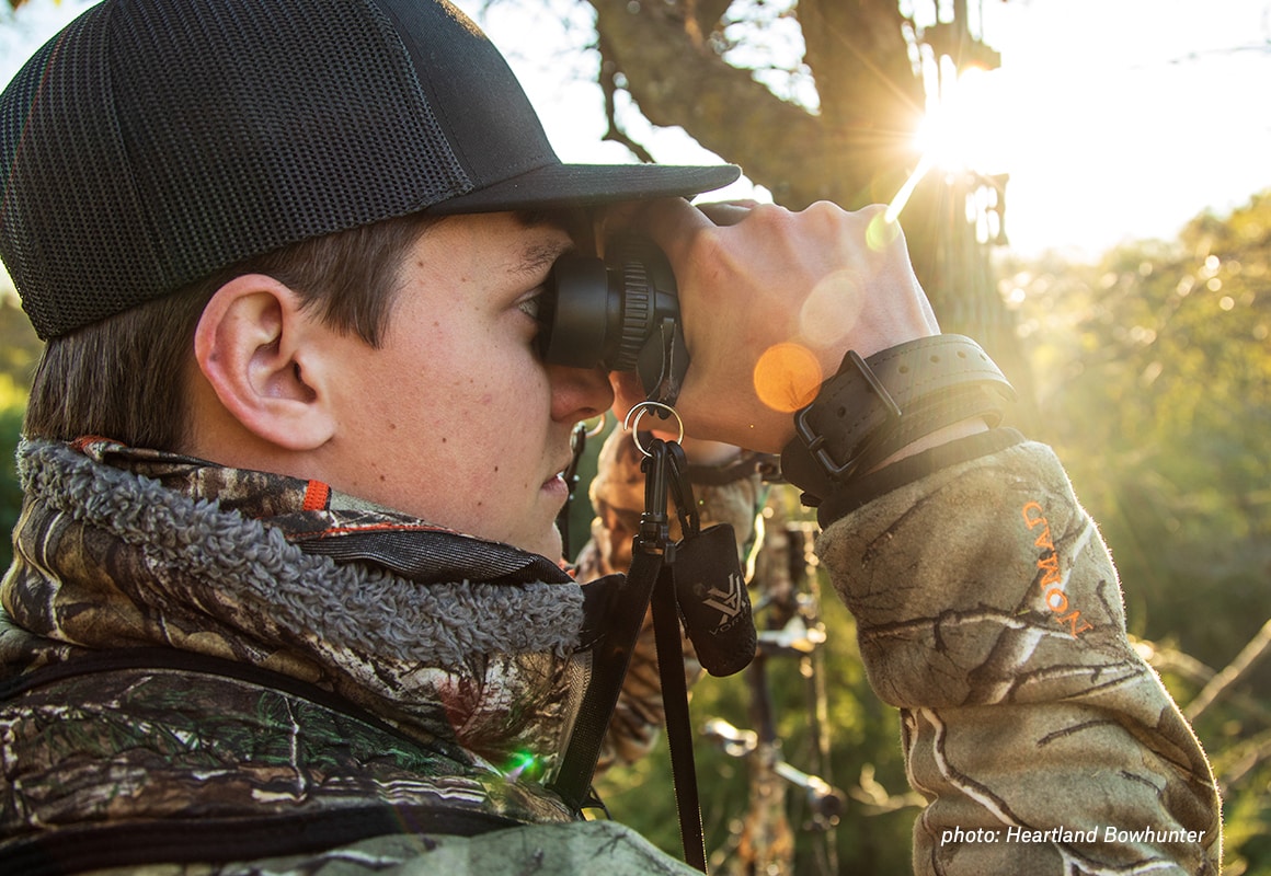 Man looking through binoculars while hunting whitetail deer.