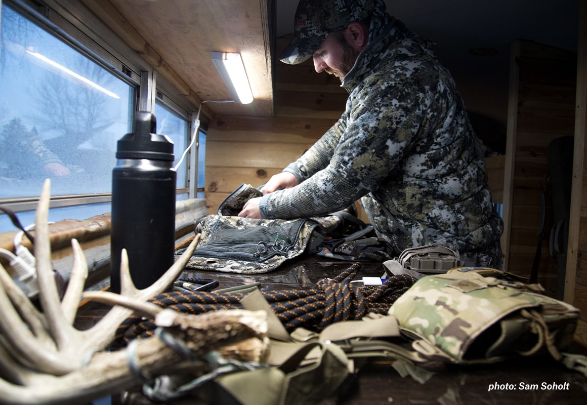 Man preparing and loading gear before heading outside to hunt.