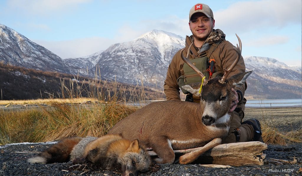 A hunter wearing an onX Hunt hat poses with the deer he harvested. 