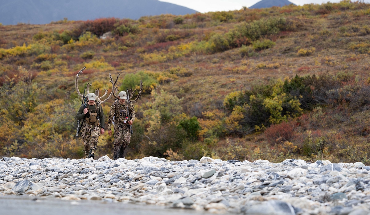 Two hunters carry out caribou meat after a successful hunt in Alaska.