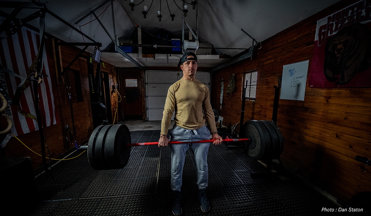Man deadlifting in a garage, training to hunt in the mountains.