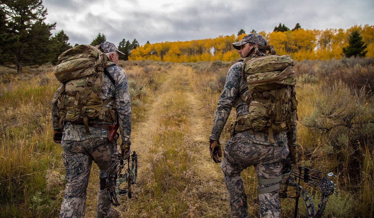 Two hunters walking on an overgrown dirt road accessing public land using an access easement.