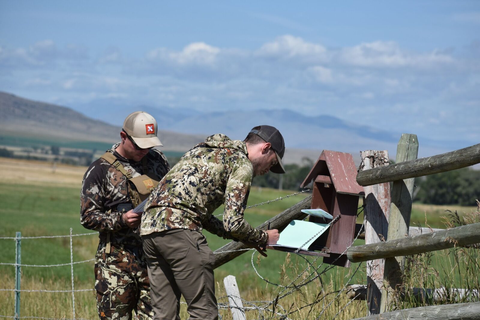 two hunters at a "walk-in" hunting program sign-in where they are signing their names so they can enter the private land that the owner is allowing them to hunt on.