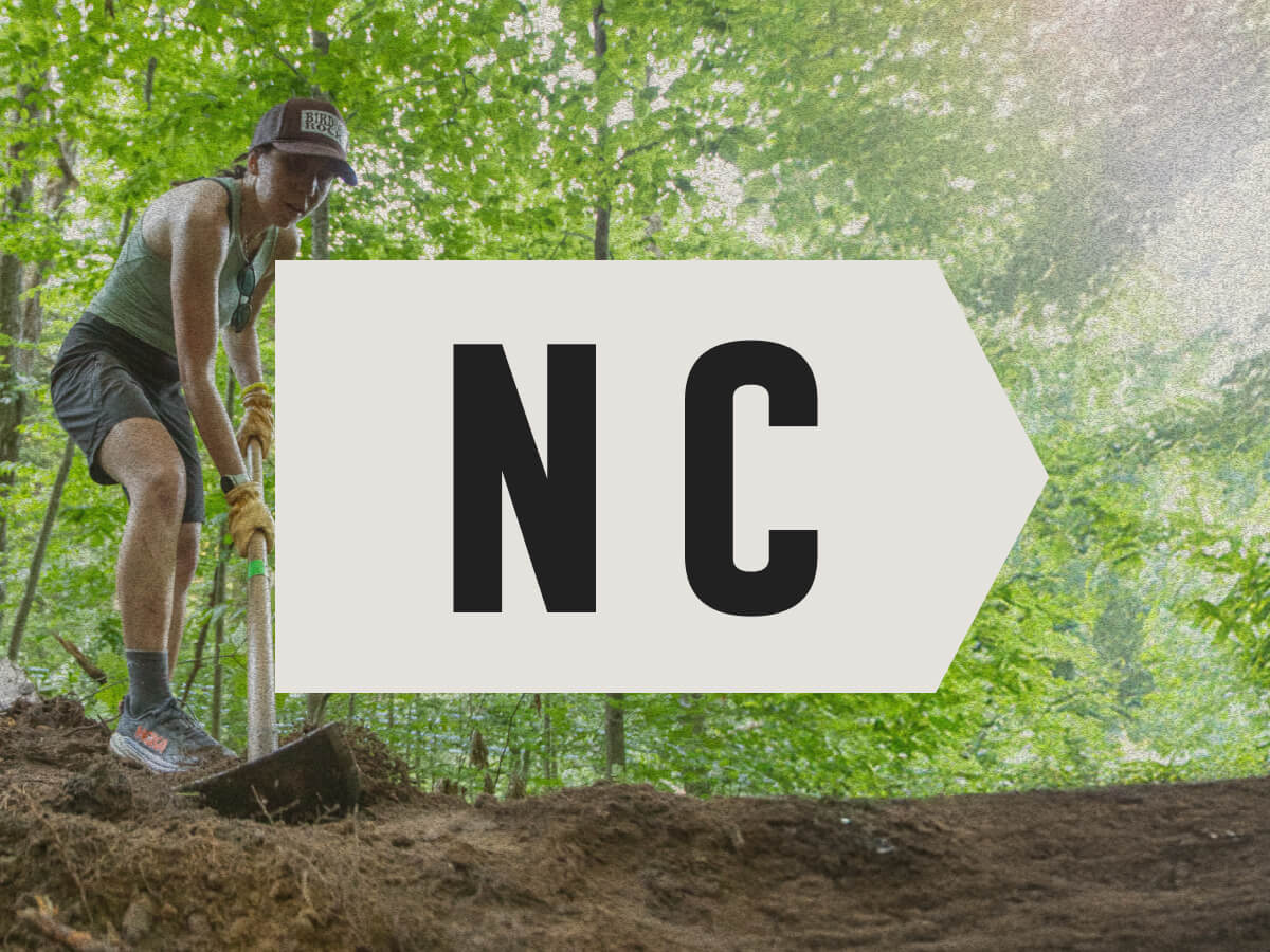 Woman with a shovel working on a trail.
