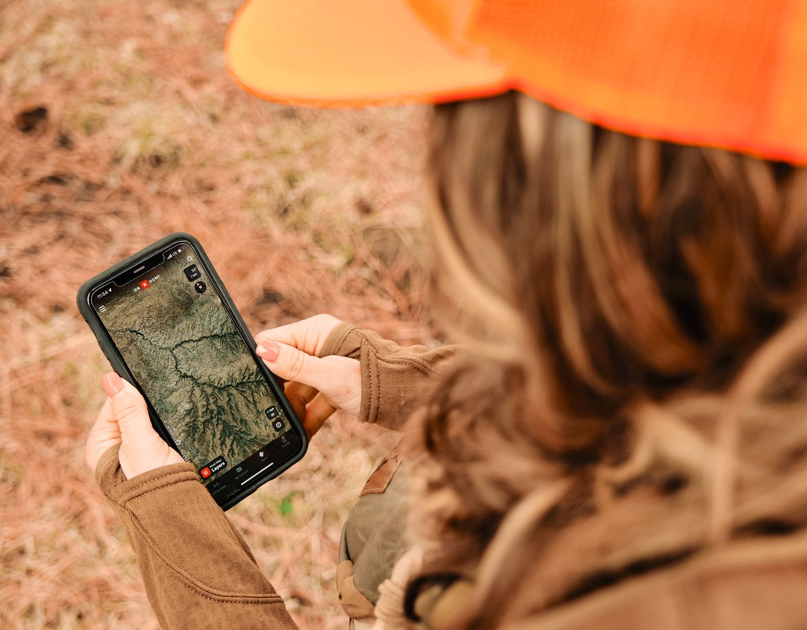 A woman uses a cell phone to look at onX Hunt maps.