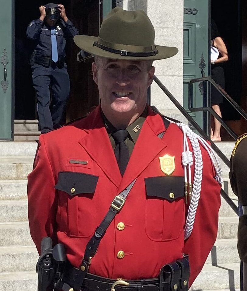 A male game warden poses in his red uniform.
