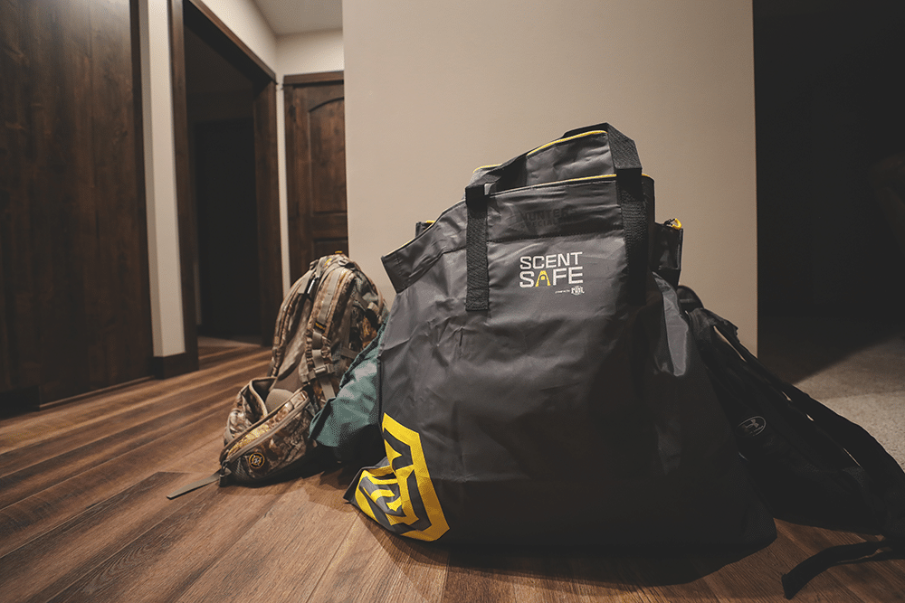Hunting gear in a pile on the hallway floor. A Scent Safe bag is in the forefront. 