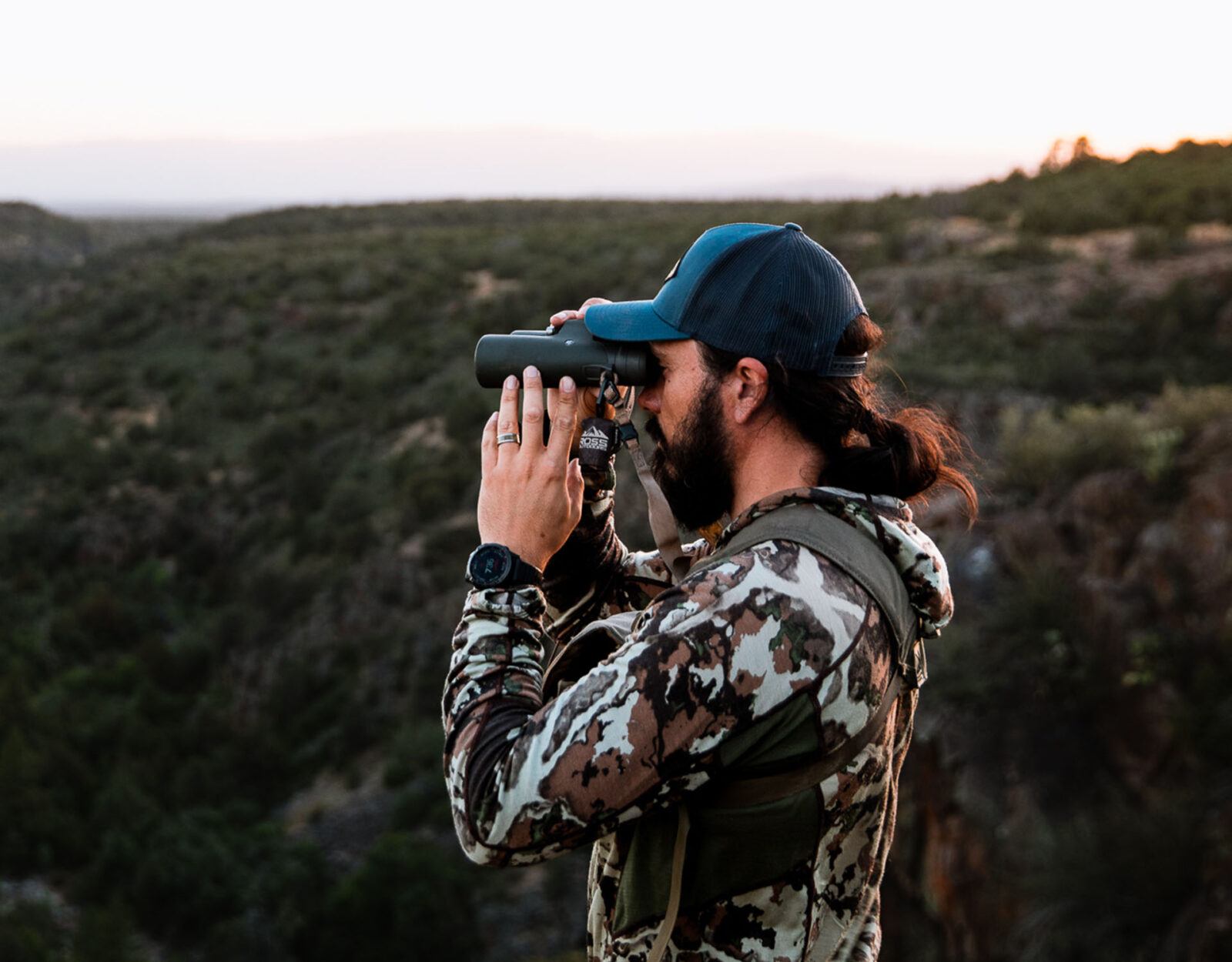 A male hunter uses binoculars to glass for wild game. 