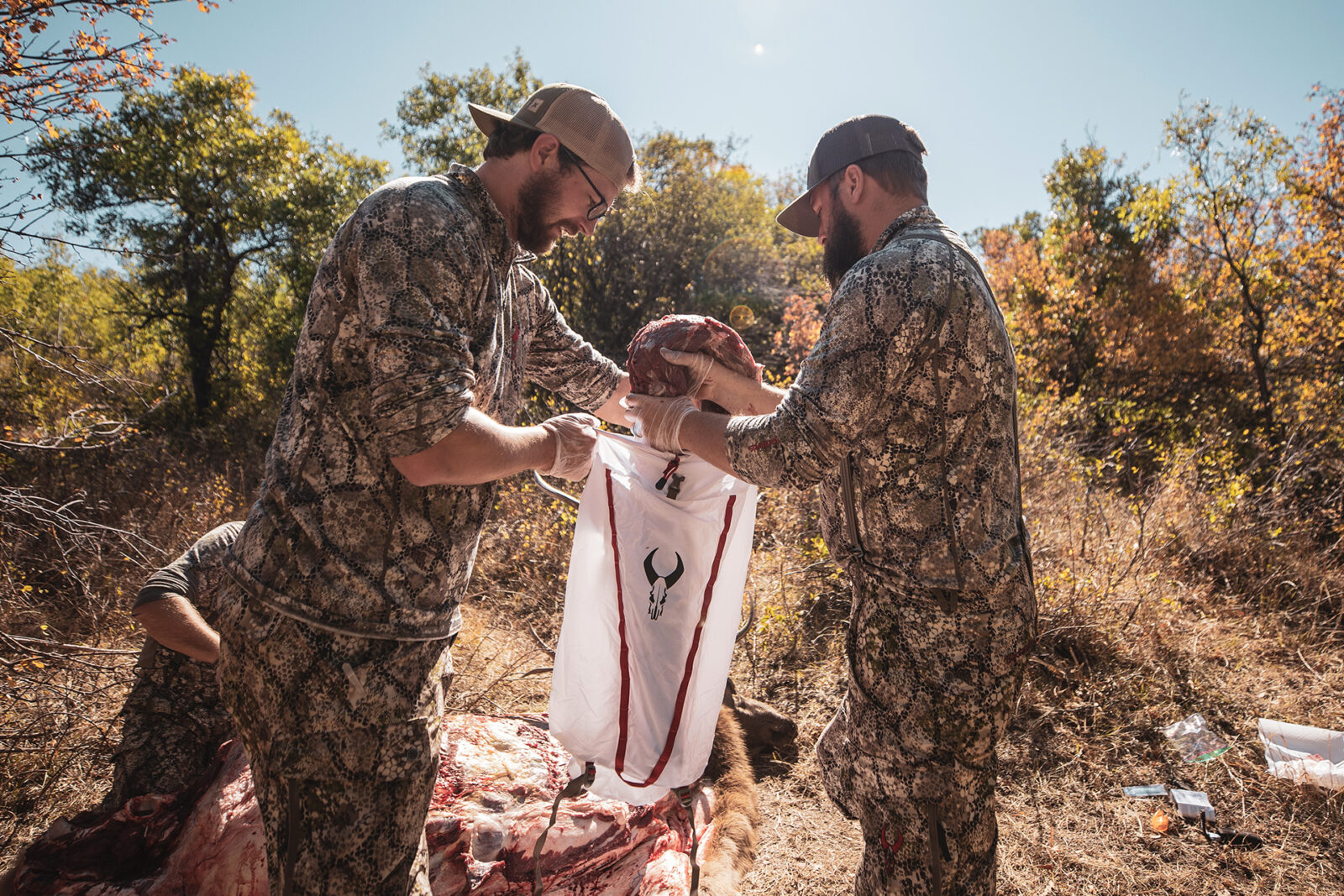 Two backcountry hunters place wild game into a game bag while field dressing their harvest.