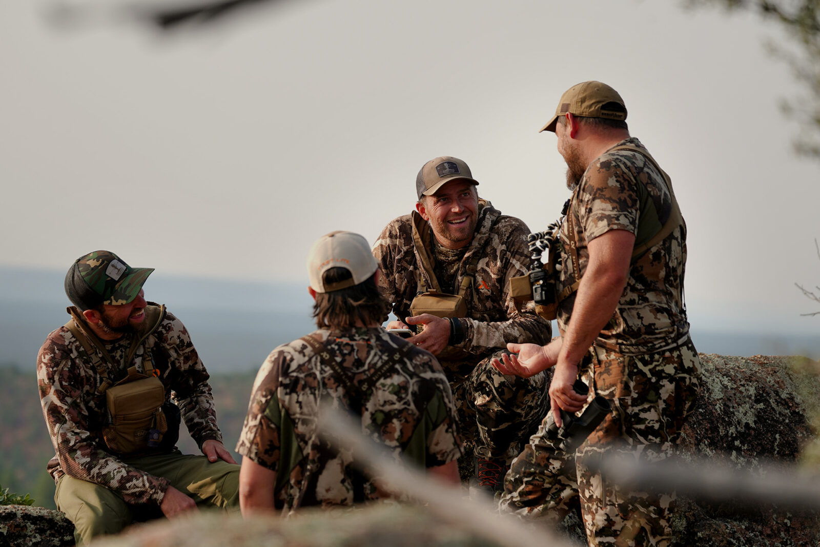 A group of four male hunters take a break to chat. 