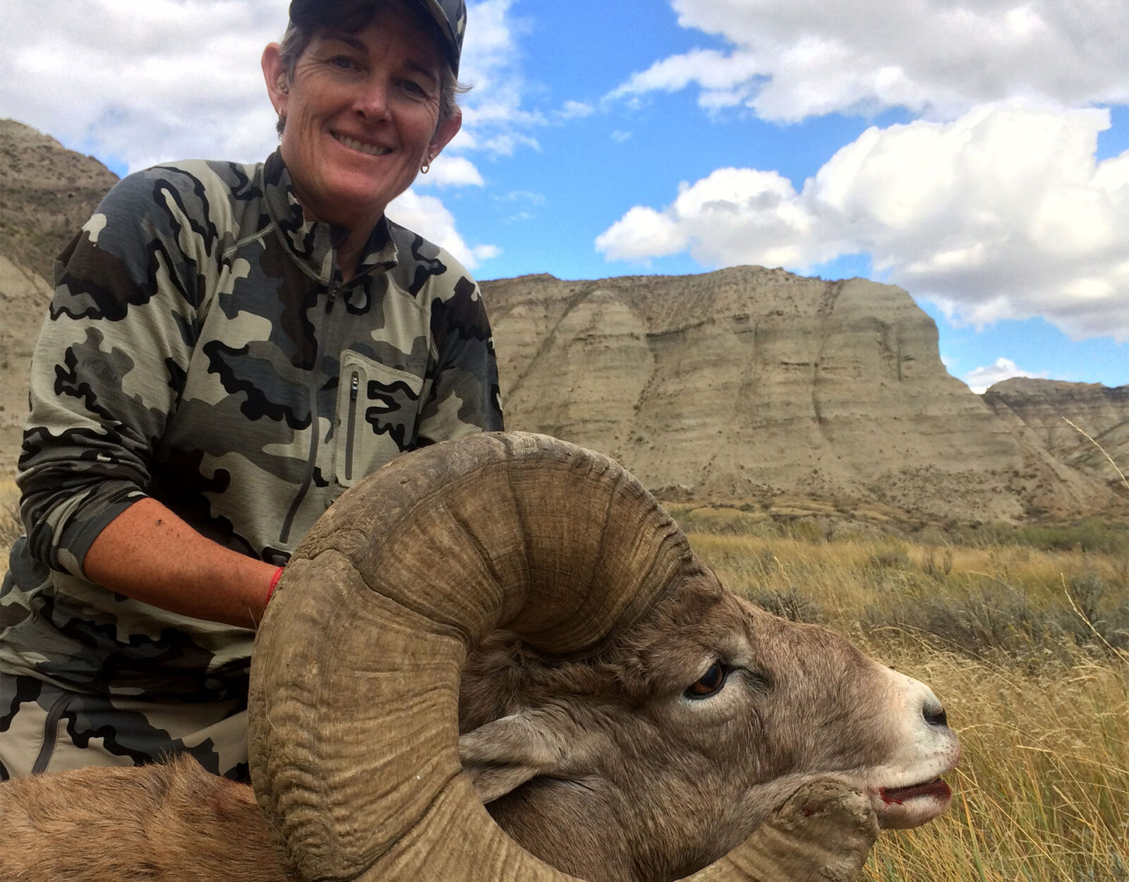 A female hunter poses with the ram she harvested. 