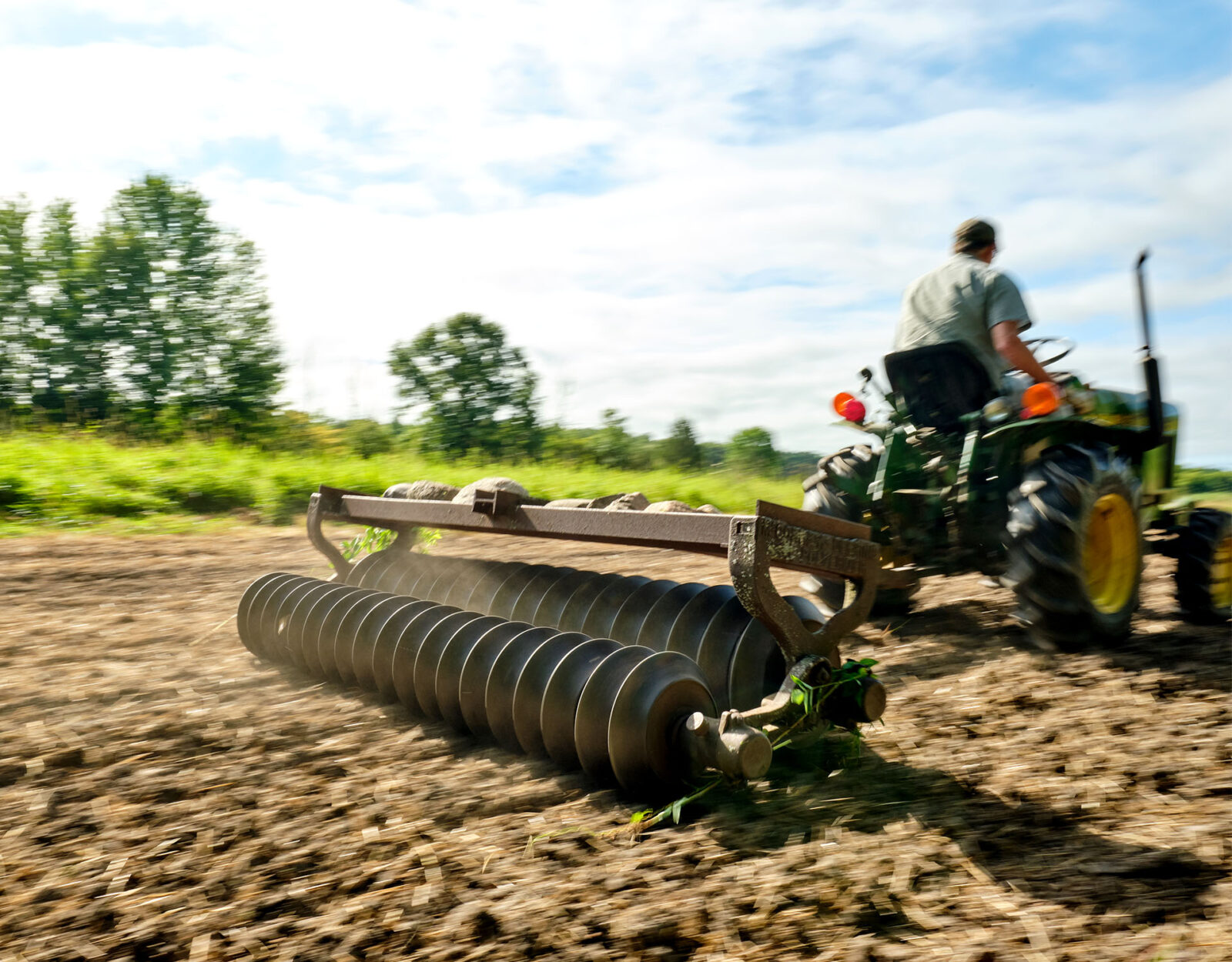 A man riding a tractor tills a food plot. 