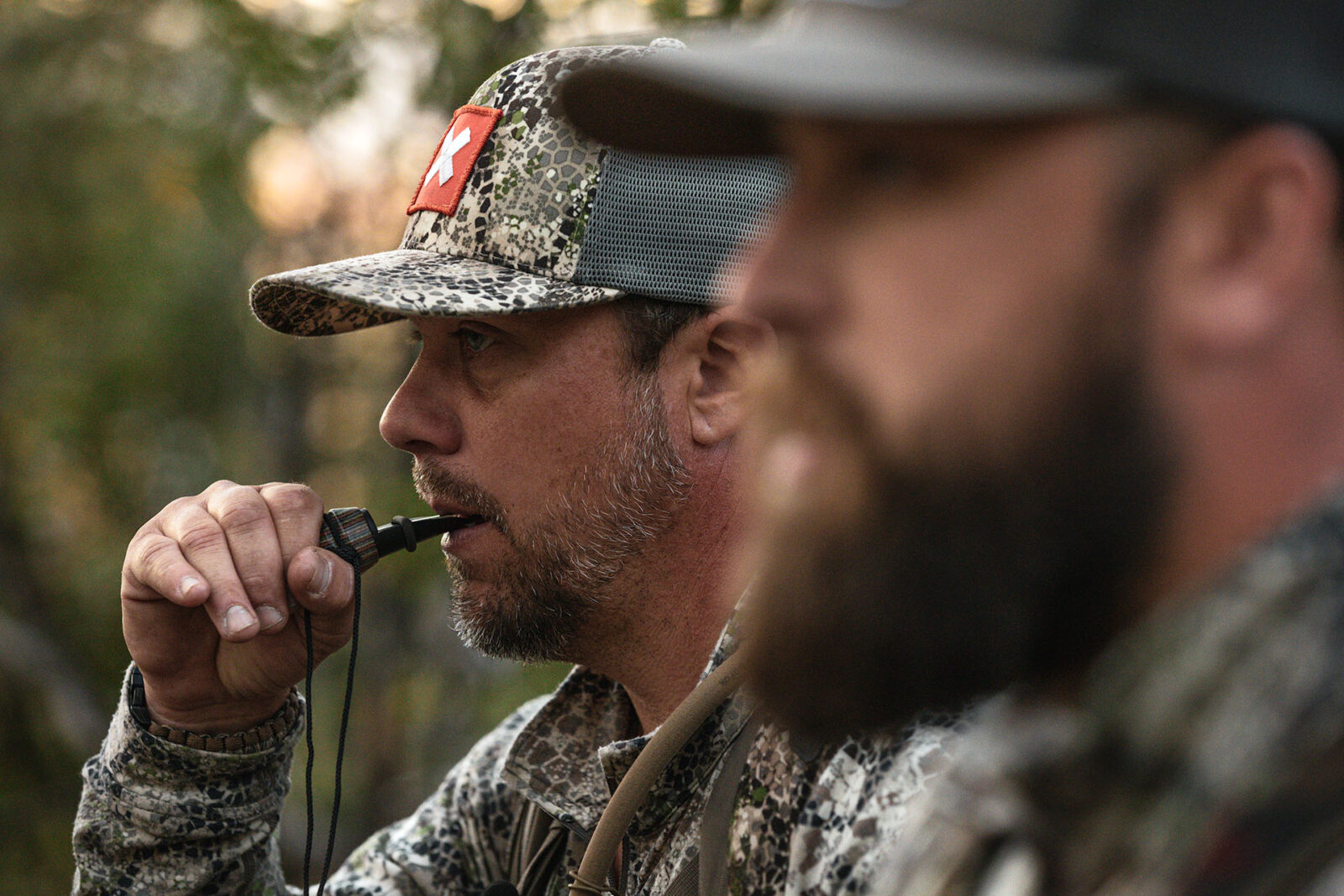 A hunter wearing an onX Hunt hat uses an elk call. 