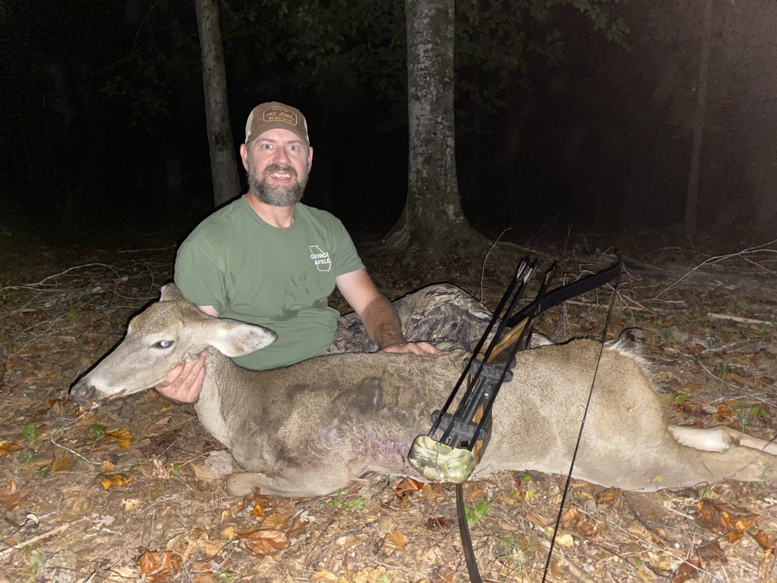 Hunter with recurve bow and a downed deer