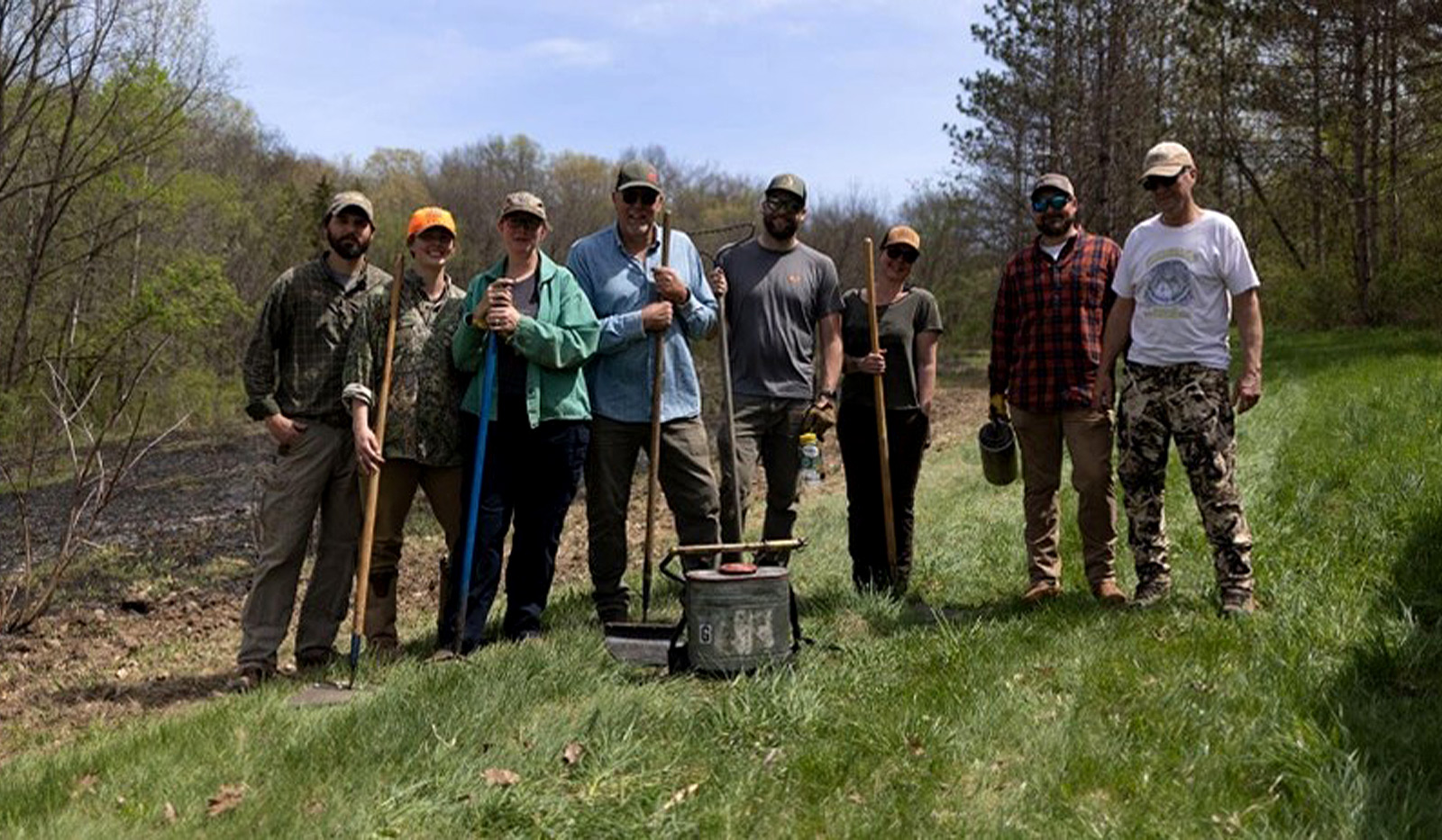 A group of men and women working on land with shovels.