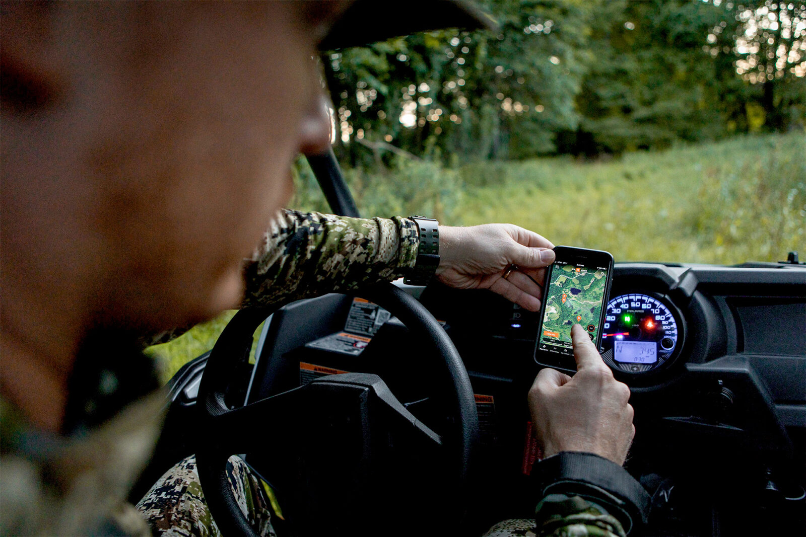 A hunter in their truck checks the map using the onX Hunt App.