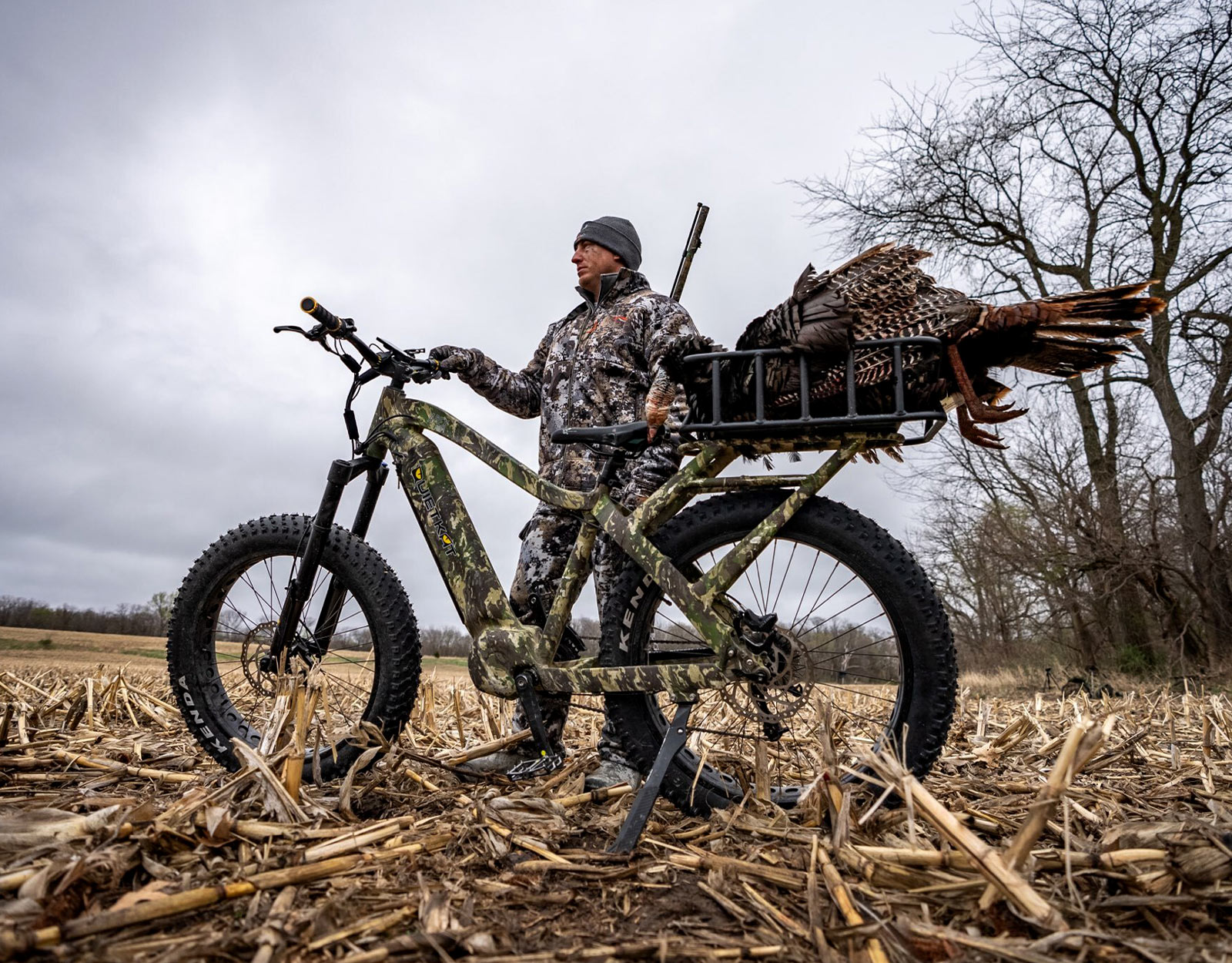a hunter with a camo electric bike for hunting with a turkey in the back of the bike