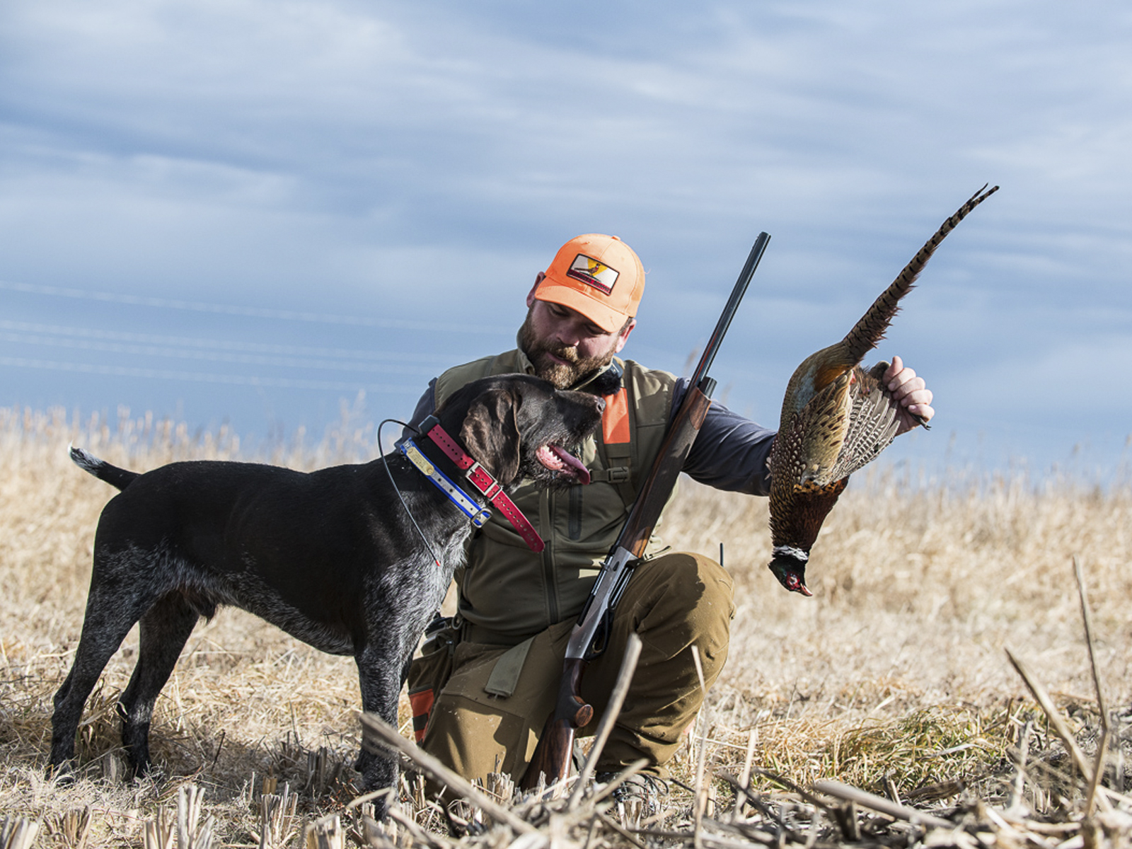 A hunter and hunting dog with a pheasant.