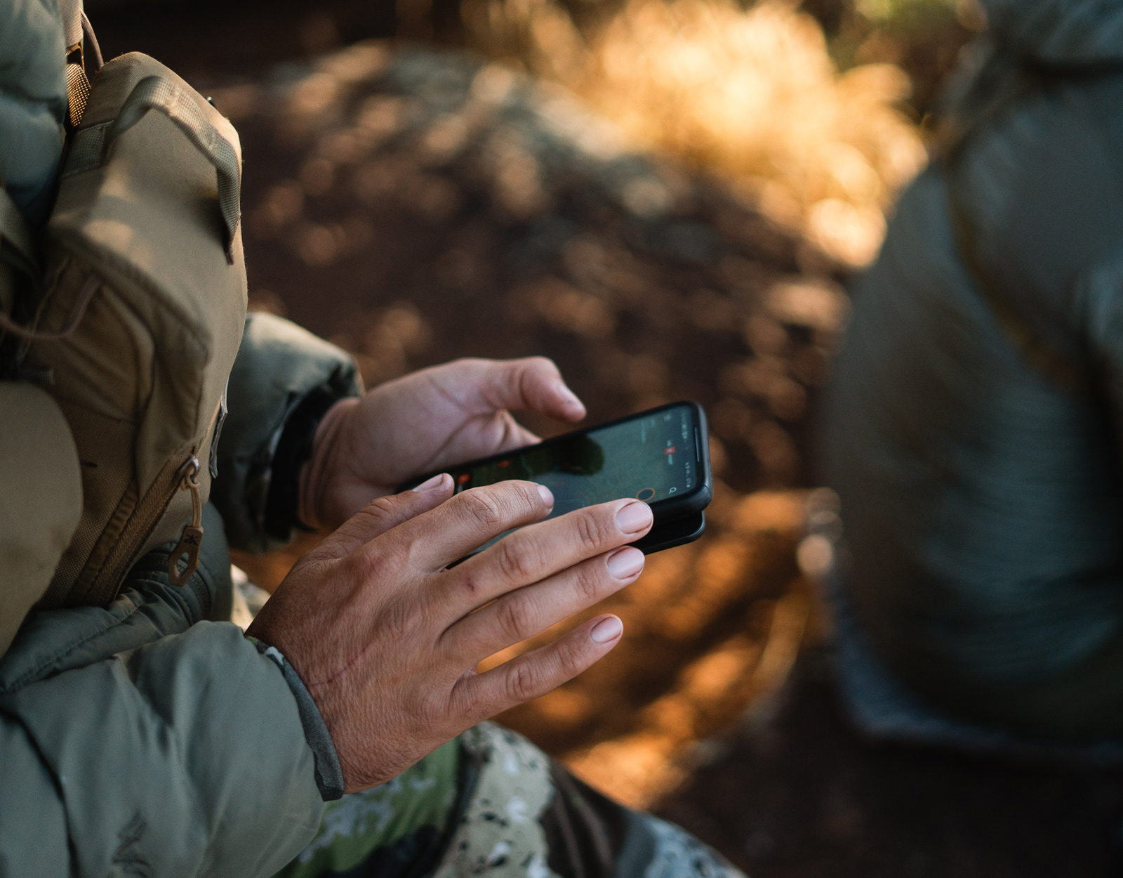 Man looking at onX Hunt App while hunting in the field.