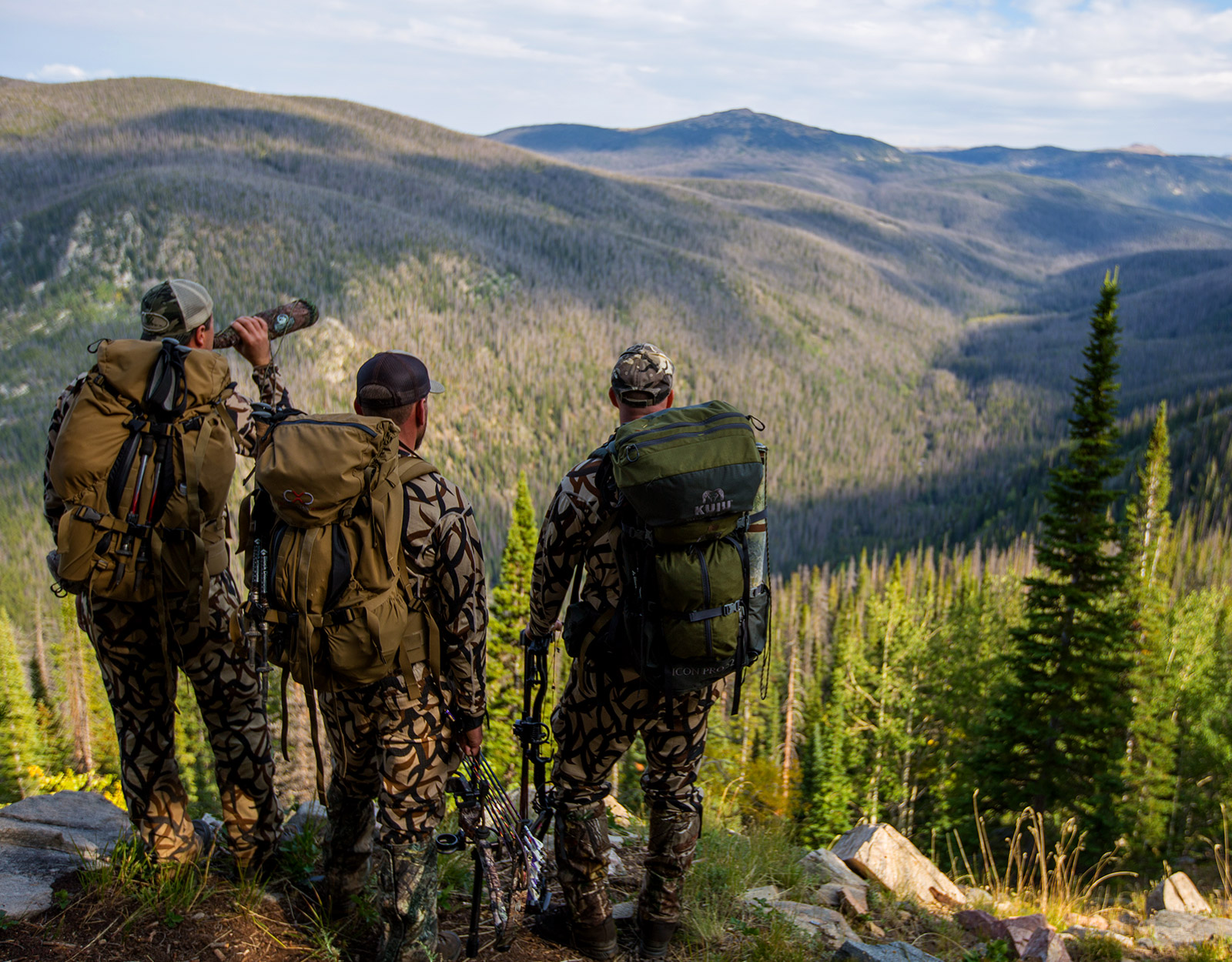 3 hunters looking over a mountain trail.
