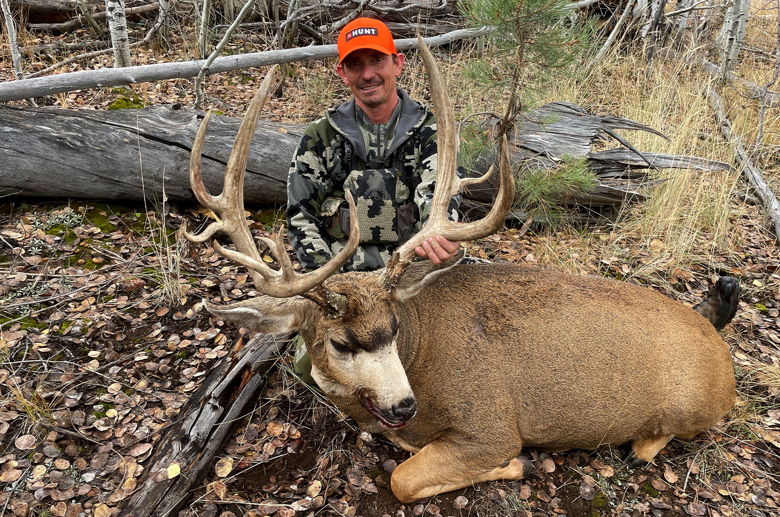 A male hunter with the mule deer buck he harvested.