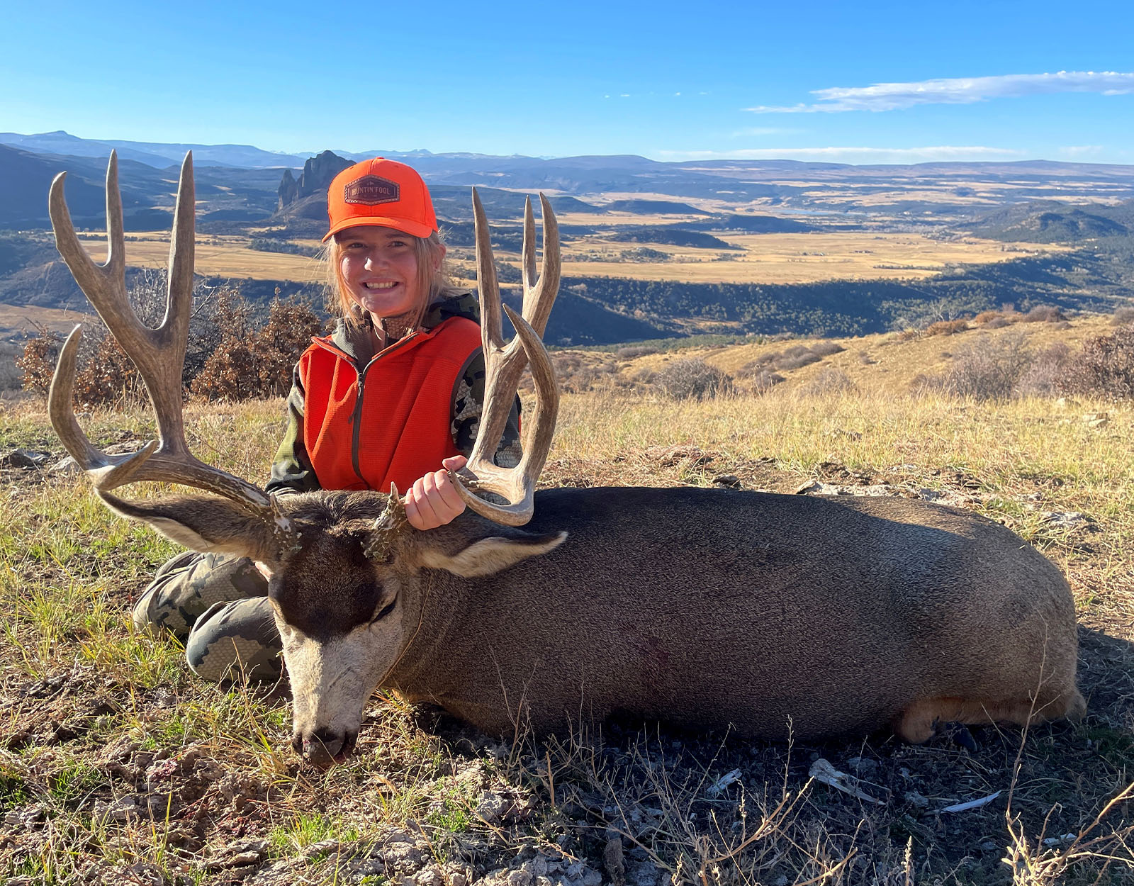A young female hunter with the mule deer buck she harvested.