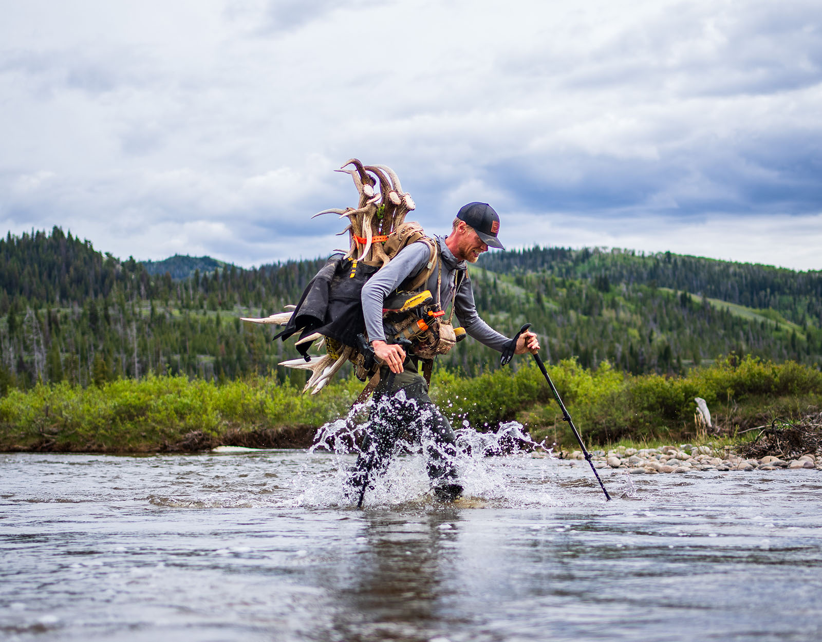 Steven Drake treks through water with a pack full of sheds on his back. 