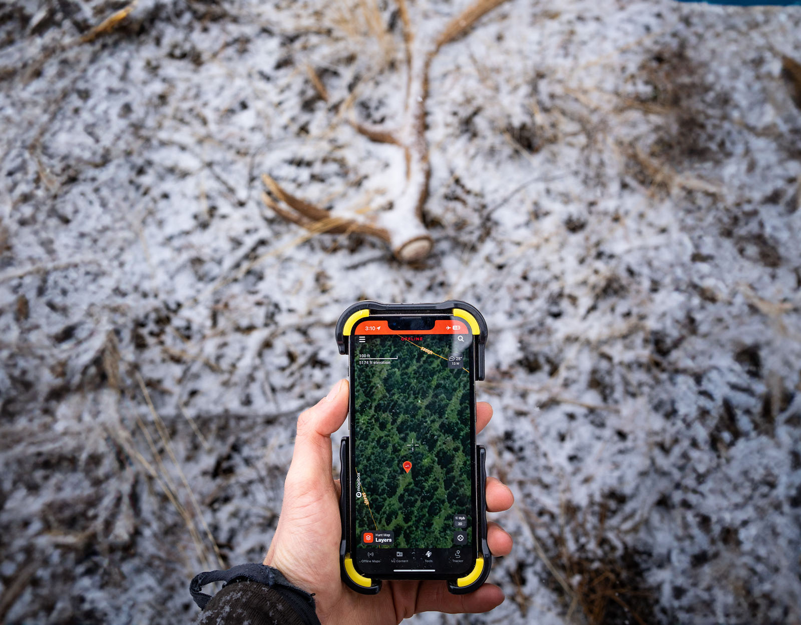 A hand holding a mobile device with onX Hunt on the screen.