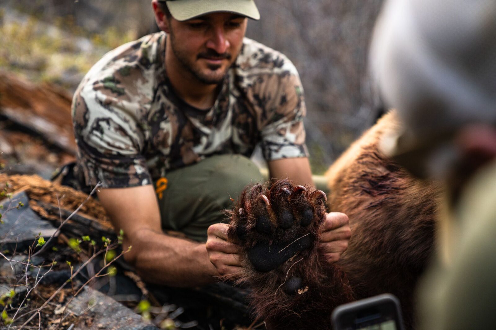 A hunter holds up the paw of a black bear he harvested.