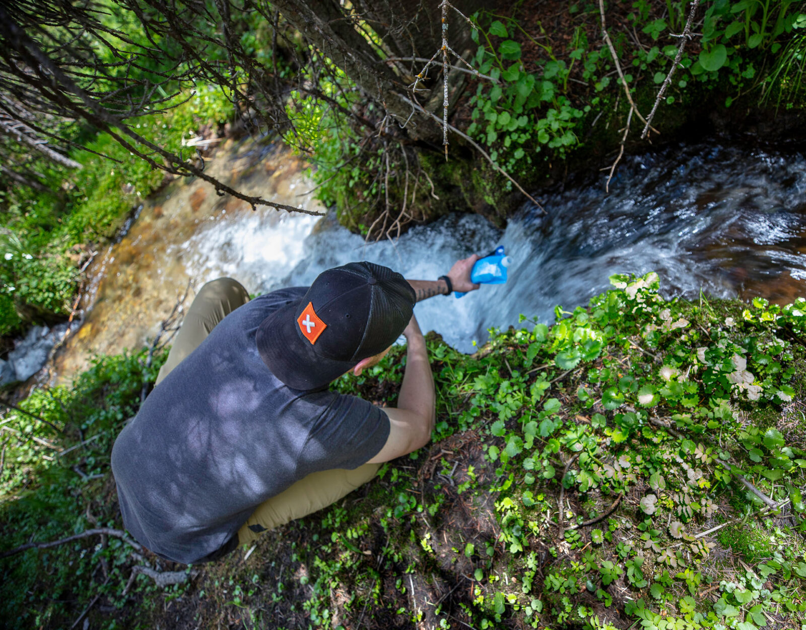A hunter fills up a water bladder from a backcountry creek.