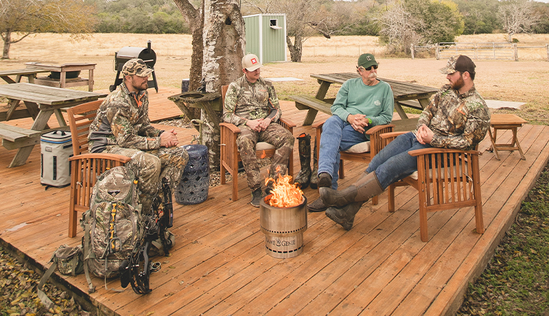 Men sit around a stove on a deck.