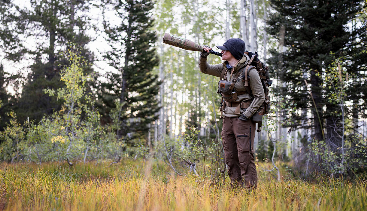 A hunter uses a bugle tube in the timber.