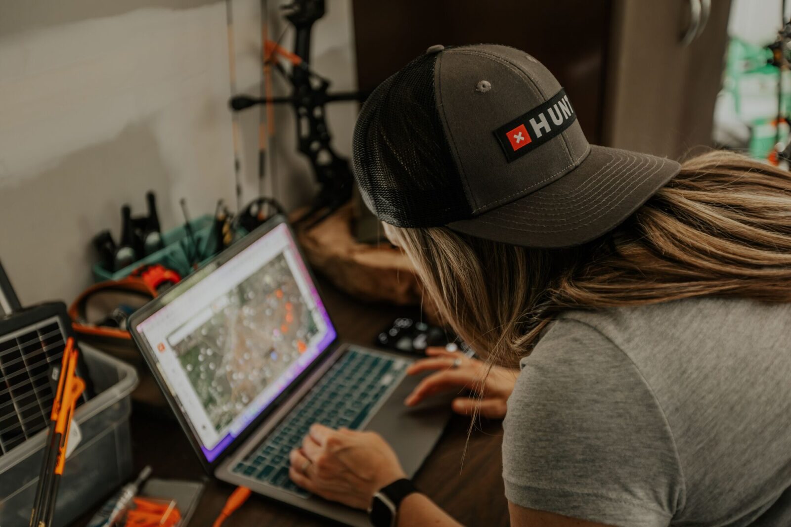 Female hunter e-scouts on laptop.
