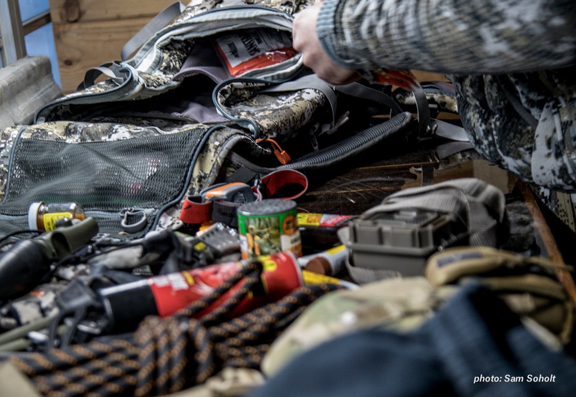 Hunter packing pack with hunting gear and medical kit in cabin.
