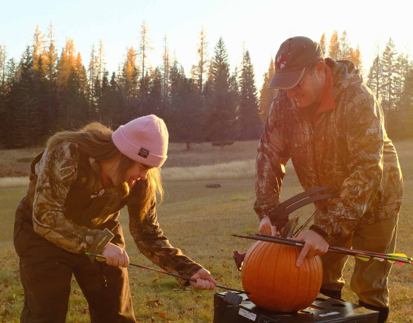 Father and daughter practicing bow hunting with a pumpkin 