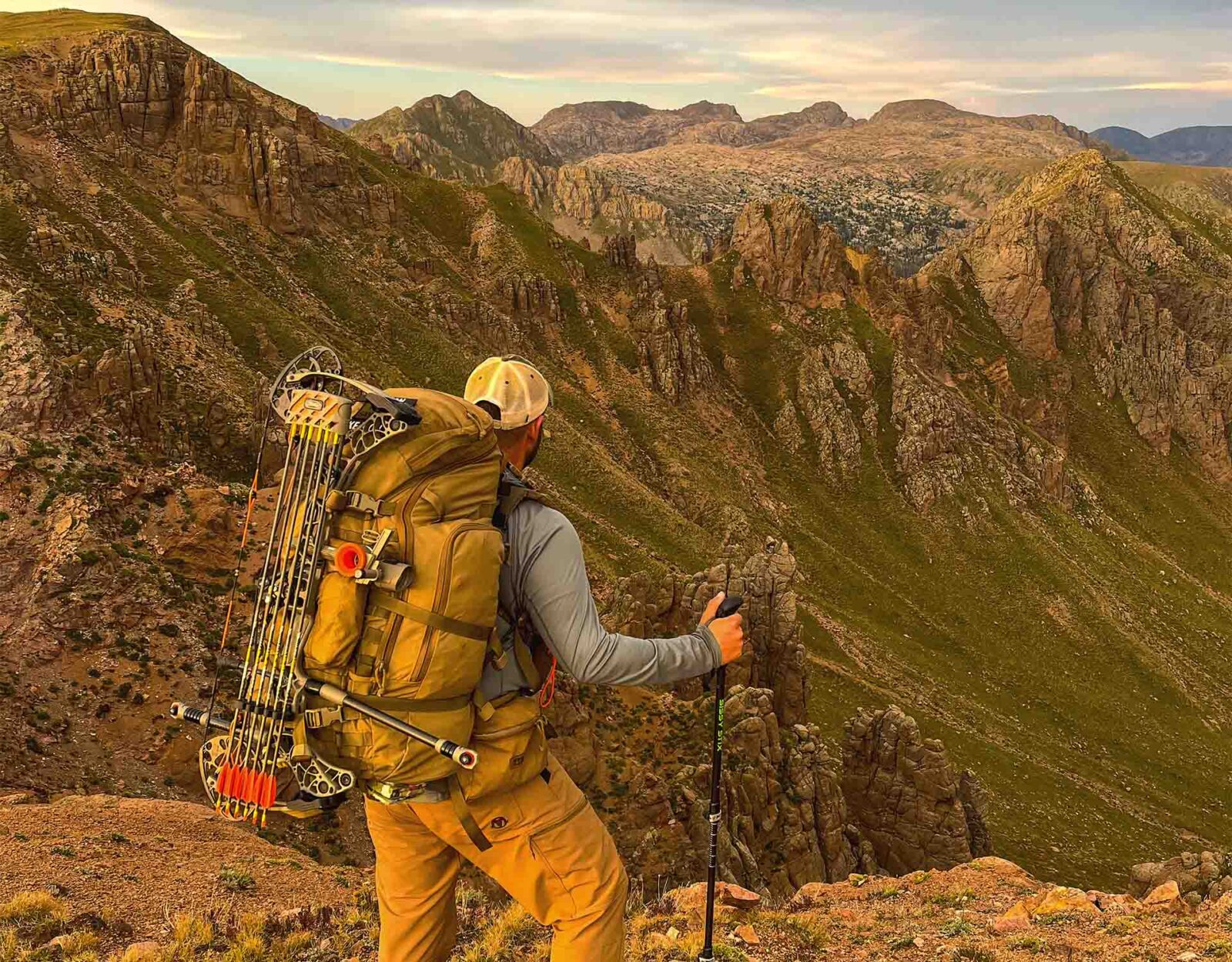 A man stands on a ridge and looks out across mountains.