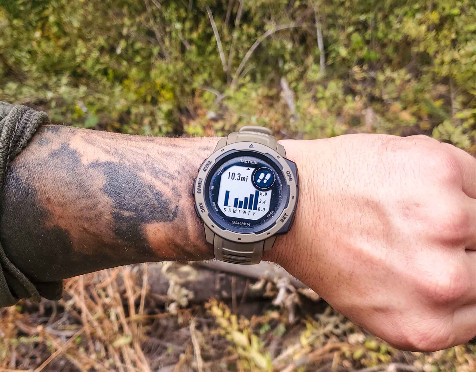 A man's tattooed wrist showing his fitness watch stats.